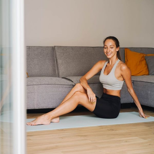 A woman smiling peacefully while stretching on a yoga mat.
