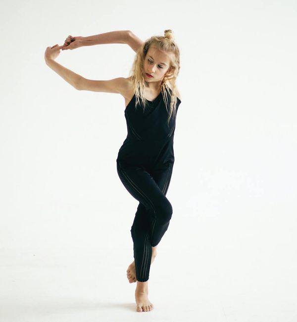 Woman performing an energetic yoga pose against a minimal background.
